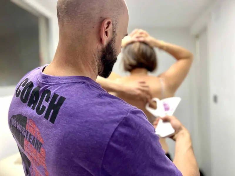 Entrenador con camiseta de coach trabajando la movilidad de una socia